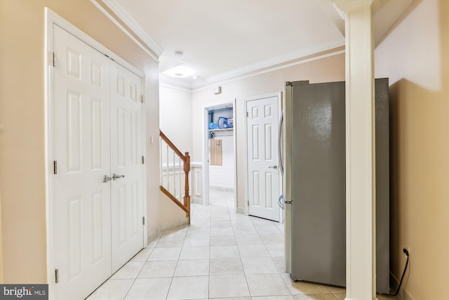 hall featuring light tile patterned flooring and crown molding