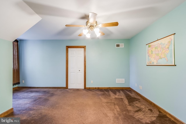 unfurnished room with dark colored carpet and ceiling fan