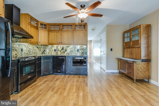 kitchen featuring wall chimney range hood, light hardwood / wood-style floors, black appliances, and backsplash