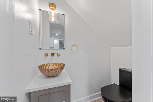 bathroom with vanity, lofted ceiling, and toilet