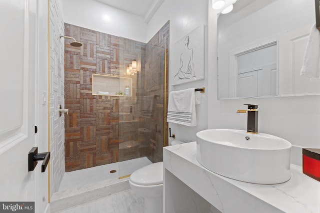 bathroom with tiled shower, vanity, and toilet