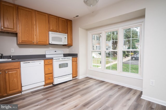 kitchen with white appliances, plenty of natural light, light hardwood / wood-style floors, and sink