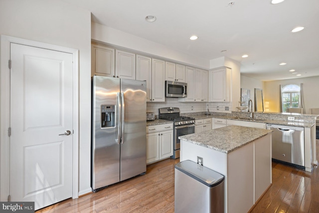 kitchen with light wood-type flooring, a center island, sink, and stainless steel appliances