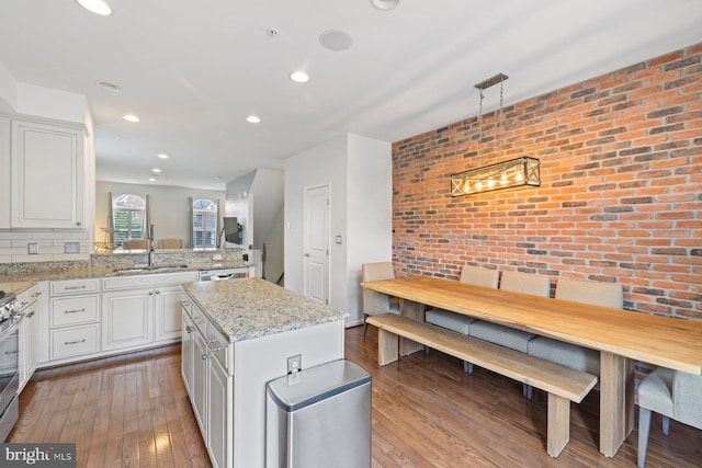 kitchen with light hardwood / wood-style floors, white cabinets, kitchen peninsula, a center island, and sink