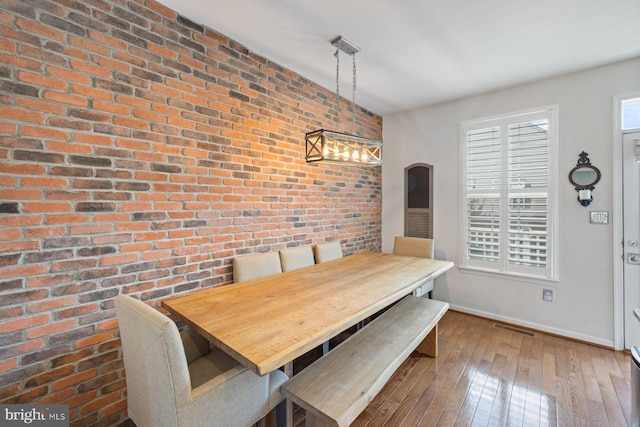 dining area featuring brick wall and hardwood / wood-style flooring