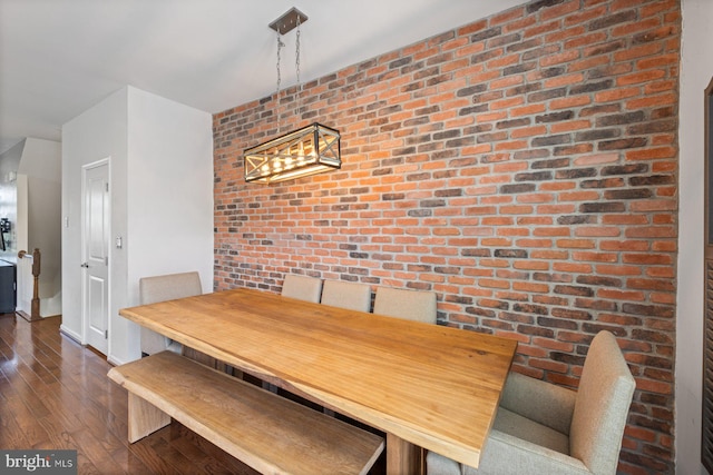 unfurnished dining area featuring brick wall and dark hardwood / wood-style floors