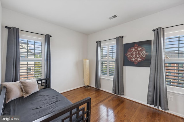 bedroom with multiple windows and dark hardwood / wood-style floors