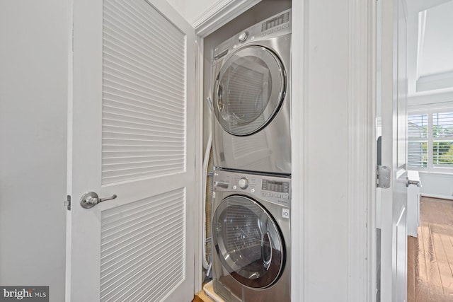 clothes washing area with hardwood / wood-style floors and stacked washer and clothes dryer