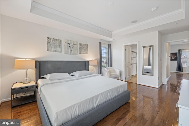 bedroom featuring wood-type flooring, a raised ceiling, and crown molding