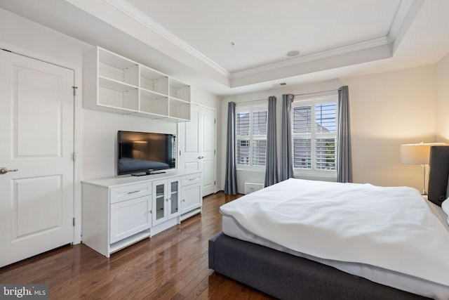 bedroom featuring ornamental molding, a tray ceiling, and dark hardwood / wood-style flooring