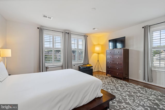 bedroom featuring multiple windows and dark wood-type flooring