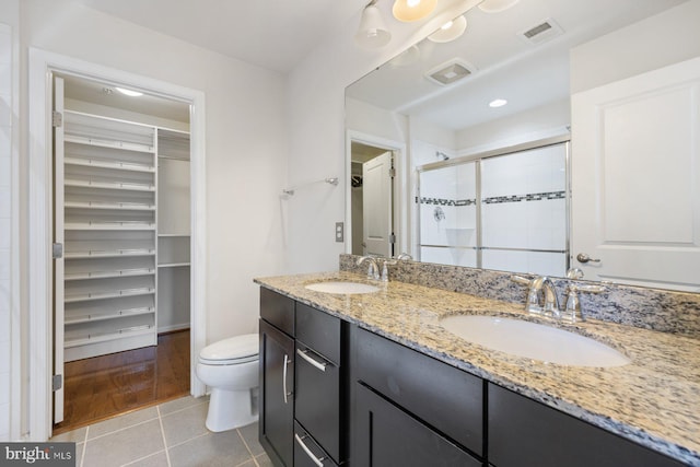 bathroom with walk in shower, vanity, tile patterned flooring, and toilet