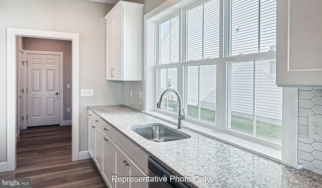 kitchen with dark wood-type flooring, sink, decorative backsplash, light stone counters, and white cabinetry