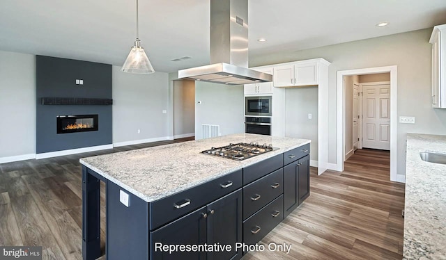 kitchen with pendant lighting, white cabinets, a fireplace, island exhaust hood, and stainless steel appliances