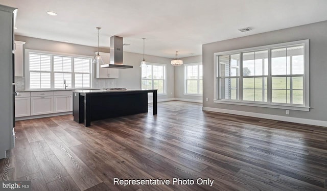 kitchen featuring island exhaust hood, sink, decorative light fixtures, white cabinets, and a center island