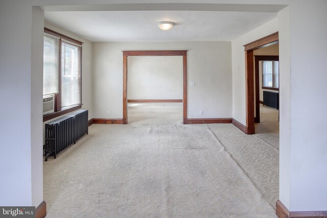 unfurnished room with radiator and light colored carpet