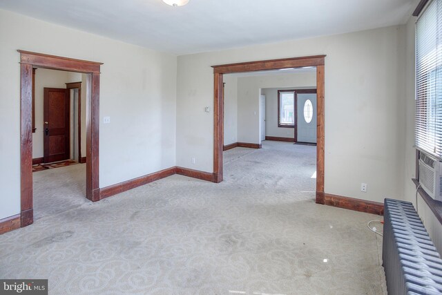 carpeted empty room featuring plenty of natural light and radiator