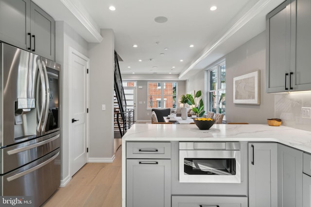 kitchen with gray cabinetry, light stone countertops, stainless steel fridge with ice dispenser, and light hardwood / wood-style flooring