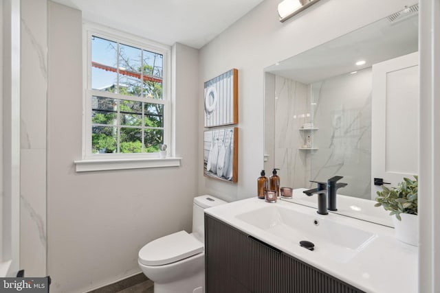 bathroom featuring vanity, toilet, and tiled shower