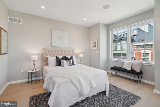 bedroom with light hardwood / wood-style floors and multiple windows