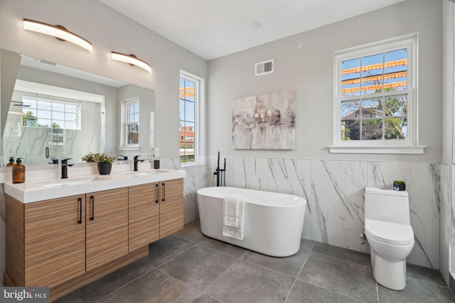 bathroom featuring tile walls, tile patterned flooring, a tub, vanity, and toilet