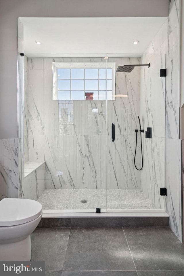 bathroom featuring a shower with shower door and toilet