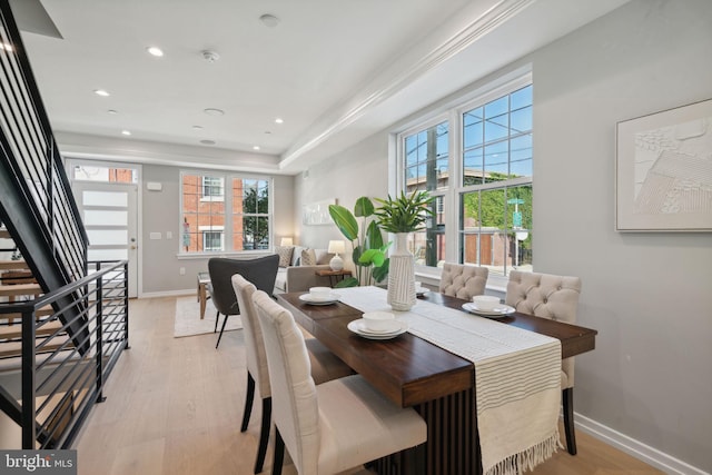 dining area featuring light hardwood / wood-style flooring, a raised ceiling, and crown molding