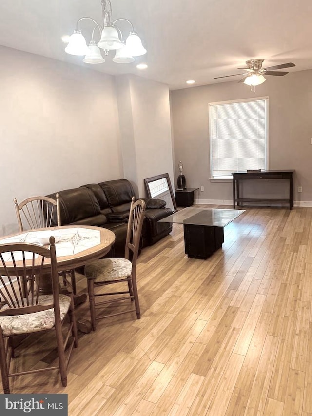 dining area with light wood-type flooring and ceiling fan with notable chandelier