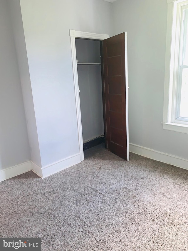 unfurnished bedroom featuring a closet and light carpet