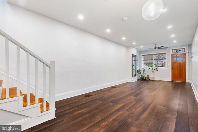 unfurnished living room with ceiling fan and dark wood-type flooring