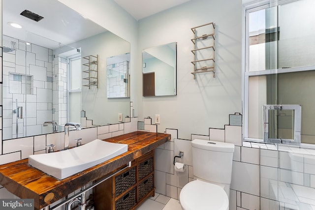 bathroom with tile patterned floors, vanity, tile walls, toilet, and a shower with shower door