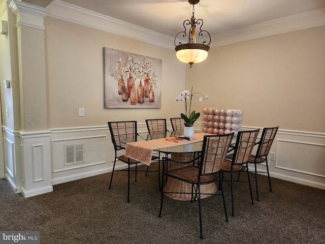 carpeted dining space featuring crown molding and decorative columns