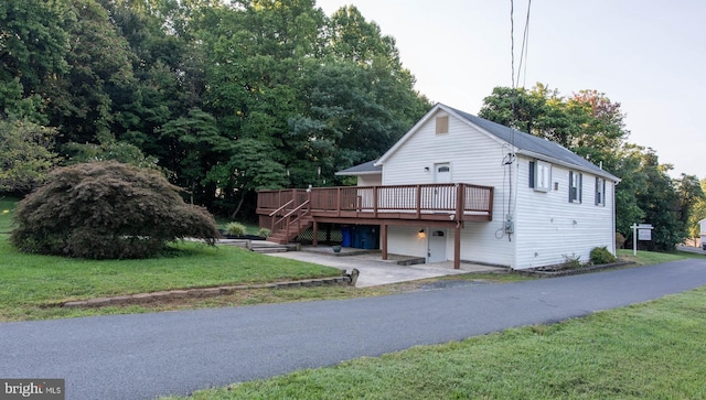 view of front of home featuring a wooden deck, a garage, and a front yard