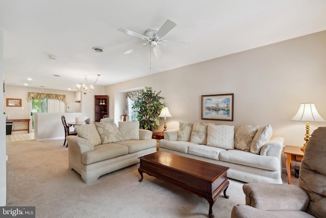 carpeted living room with ceiling fan with notable chandelier