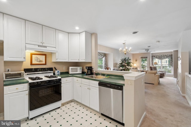 kitchen with a wealth of natural light, kitchen peninsula, white appliances, and white cabinets