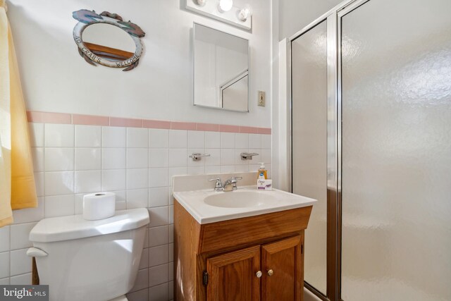 bathroom featuring tile walls, walk in shower, vanity, and toilet