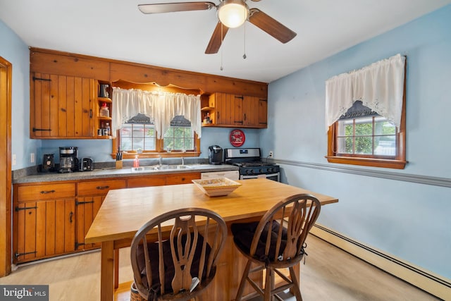 kitchen featuring gas stove, baseboard heating, sink, and a wealth of natural light