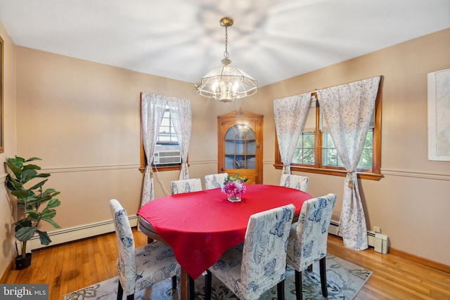 dining space featuring hardwood / wood-style flooring, baseboard heating, and a chandelier