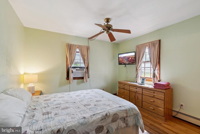 bedroom with ceiling fan, a baseboard radiator, and hardwood / wood-style floors