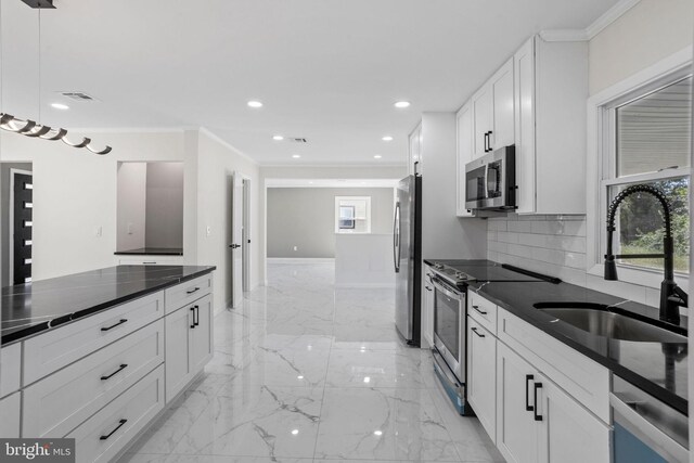 kitchen featuring pendant lighting, appliances with stainless steel finishes, crown molding, decorative backsplash, and white cabinets