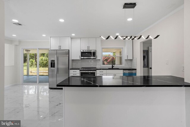 kitchen featuring appliances with stainless steel finishes, white cabinetry, plenty of natural light, and decorative light fixtures