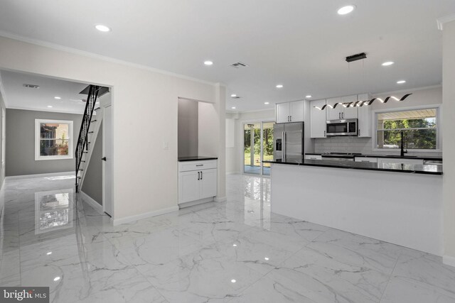 kitchen with appliances with stainless steel finishes, hanging light fixtures, white cabinetry, and a healthy amount of sunlight