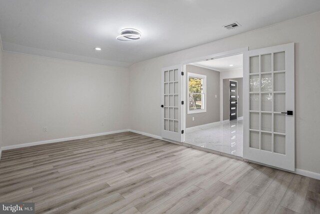 empty room with light hardwood / wood-style floors and crown molding