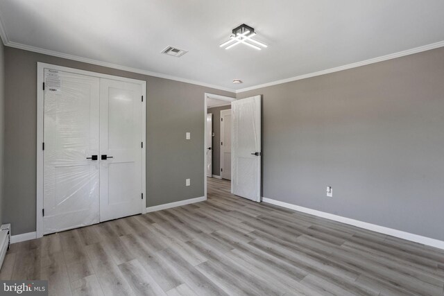 unfurnished bedroom featuring ornamental molding, a closet, and light hardwood / wood-style floors