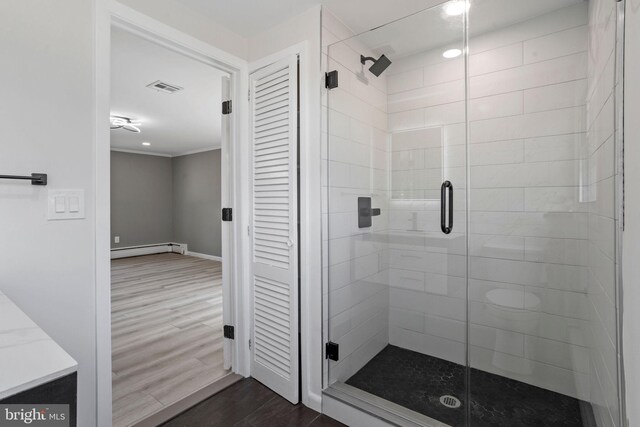 bathroom with hardwood / wood-style floors, a shower with door, and a baseboard heating unit