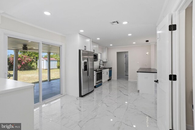 kitchen featuring tasteful backsplash, crown molding, hanging light fixtures, stainless steel appliances, and white cabinetry