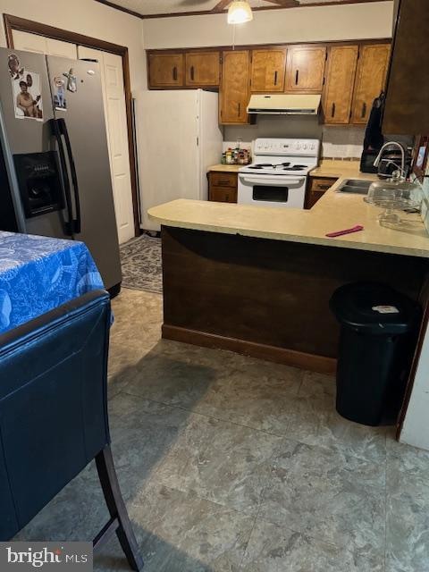 kitchen featuring a breakfast bar, sink, kitchen peninsula, white appliances, and ceiling fan