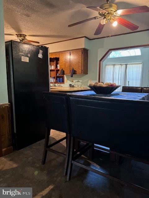 kitchen with a textured ceiling, ceiling fan, and black fridge