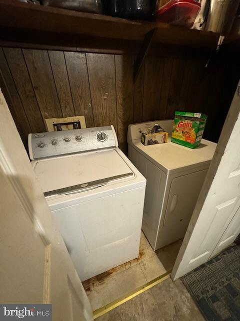 laundry area featuring wooden walls and independent washer and dryer