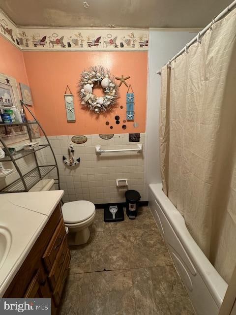 full bathroom with vanity, tile walls, toilet, and shower / tub combo with curtain